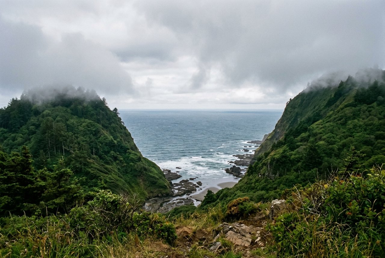 A gap between two green ridges opening onto the open Pacific, cloud sitting on the tops, no vessels