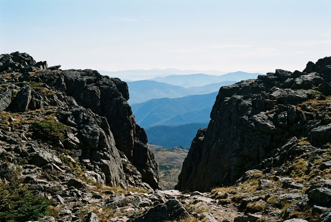 A high notch in a ridge with successive lines of blue hills visible one behind another through the gap, clear cold light